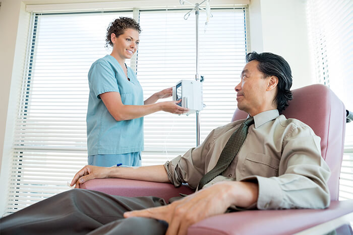 Female medical professional connecting male patient to an IV.