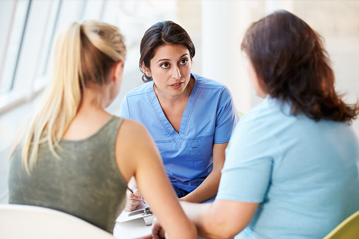Female health professional talking to mother and daughter.