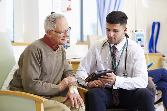 Male doctor showing male patient information on an iPad.