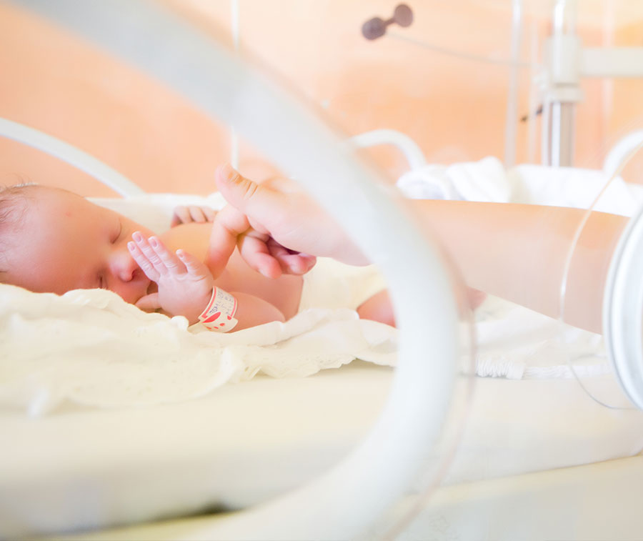 Mother touching baby in incubation.