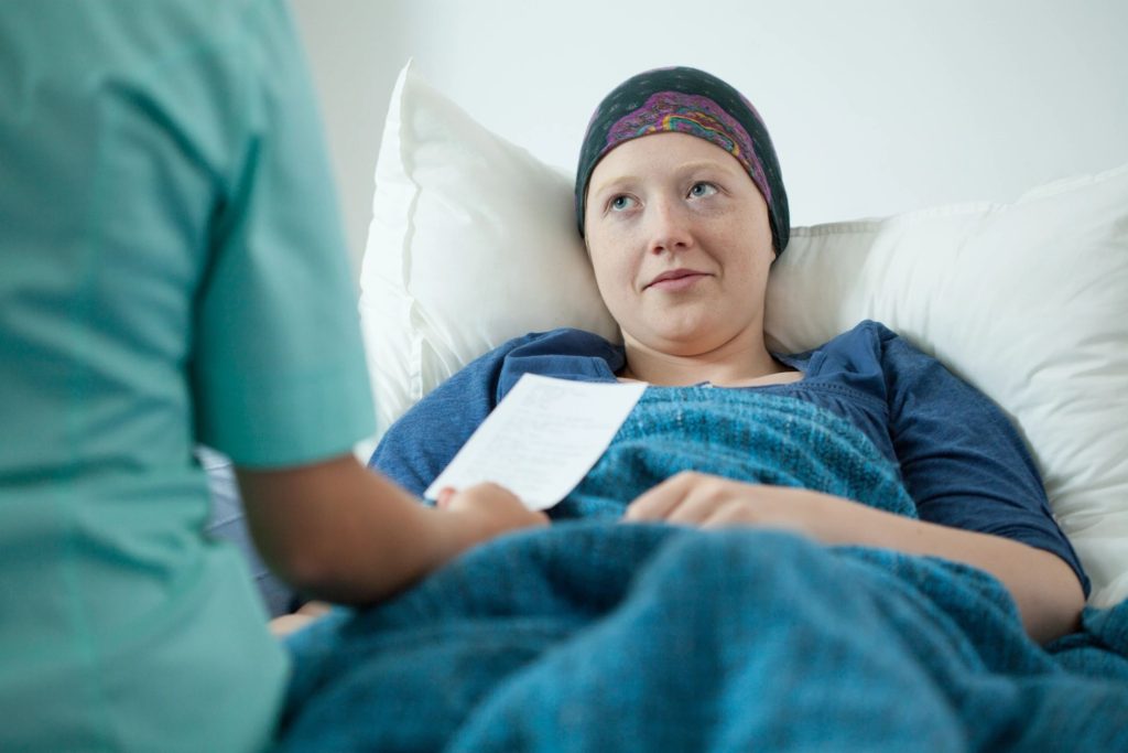 Patient in bed with medical professional discussing brochure.