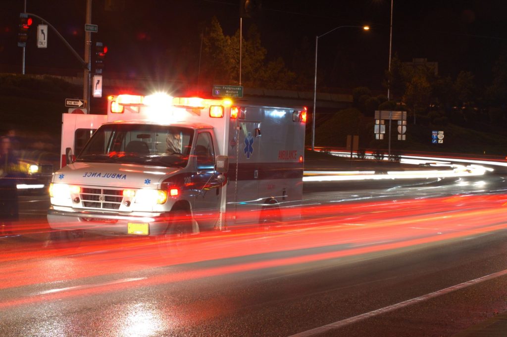 Ambulance driving down road at night.